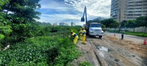 Água Pura: Limpeza do Rio Pavuninha, 2 homens da prefeitura limpam a margem do Rio
